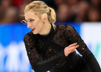 Amber Glenn, wearing a beeded black costume, looks to the side, with one arm lifted and one hanging down.