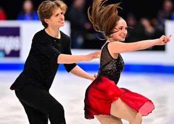 Oona Brown, dressed in a black top and a red dress, and Gage Brown, dressed in all black, showcase a fun routine with smiles and excitment.