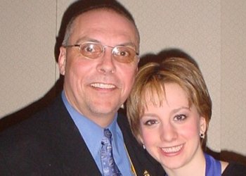 Photo of Charlie Cyr and Sarah Hughes. Cyr (left) is an older white man wearing glasses, a blue collared shirt and black suit jacket. Hughes (right) is a young white woman with short blonde hair wearing a black top