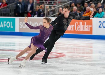 Dressed in purple, Alisa Efimova skates side by side with pairs partner Misha Mitrofanov, dressed in black.