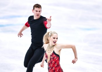 Brandon Frazier looks on at partner Alexa Knierim as she performs for the judges at the World Championships