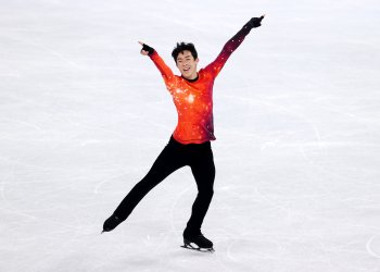 Nathan Chen in an orange spacey sweater performing his free skate at the Olympic Winter Games Beijing 2022