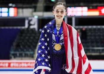 Isabeau Levito draped in the American flag with the gold medal around her neck.
