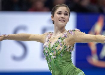 Dressed in green, arms extended, Isabeau Levito competes at the World Championshps