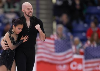 Danny O'Shea pumps his fist as he puts his other arm around partner Ellie Kam as they skate off the ice at Skate Canada International