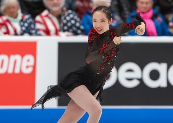 Josephine Lee, in a black dress with red flower petal details, skates to the right during her free skate at the 2024 Prevagen U.S. Figure Skating Championships.