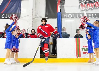 The Twisted Toepicks, dressed in blue, cheer on the Philadelphia Rebels, dressed in red, as they take the ice for their hockey game.