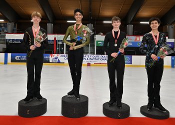 four male skaters stand on the junior men's podium at the 2024 U.S. Collegiate Figure Skating Championships. They all have medals around their neck and are holding flowers