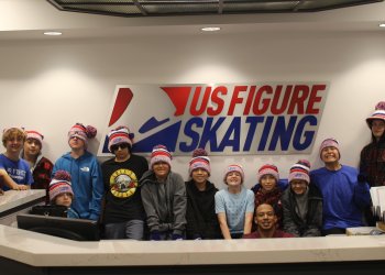 The group of students representing the Sims-Fayola Foundation stand in front of a U.S. Figure Skating sign at the U.S. Figure Skating headquarters