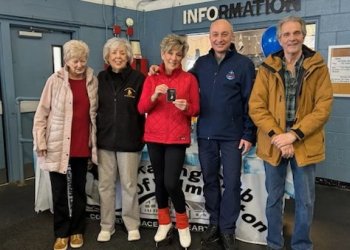 Sharon Rzaza, red coat, receives her ice dance gold medal, surrounded by friends and her coach.