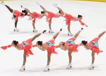 Team Image in two lines of four each, with each athlete performing a spiral. They wear coral dresses with light blue and pink details.