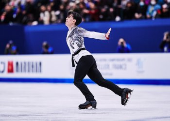 Vincent Zhou, wearing black pants and a white top, looks towards the crowd as he skates to his right at the World Championships