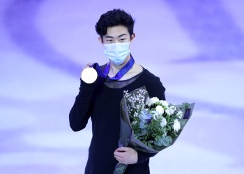 Nathan Chen stands with his medal and flowers on ice at the 2021 World Championships.