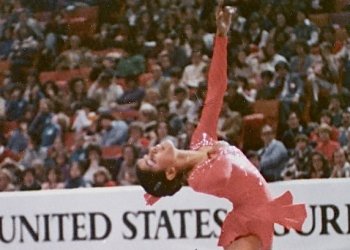 Joan Campbell completes a spin on the ice during the 1980 U.S. Championships. She is a young African American skater wearing a pink skating costume. 