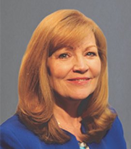 Headshot of Cecilia Peat. She is an older white woman with shoulder length red hair wearing a blue shirt