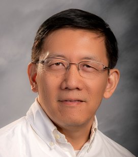 Headshot of an Asian man smiling. He is wearing a white button down shirt and glasses