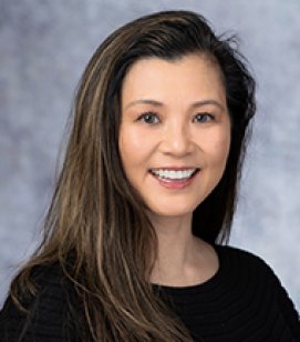Headshot of Kyoko Ina. She is an Asian woman with long brown hair. She is wearing a black shirt 