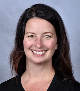 Headshot of a Caucasian woman smiling. She has long black hair and is wearing a black shirt. 