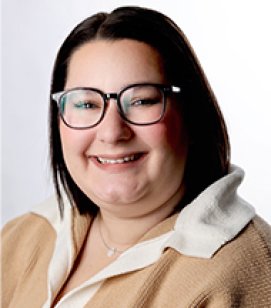 Headshot of Sammie Lisberg. Sammie is a white woman with shoulder length black hair. She is wearing a white collared shirt with a tan sweater over the top of it and glasses. 